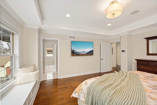 bedroom featuring wood finished floors, a tray ceiling, baseboards, and visible vents