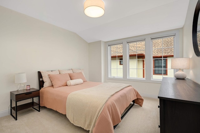 bedroom featuring baseboards, vaulted ceiling, and light carpet