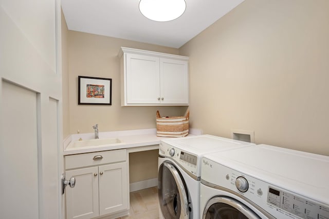 washroom with washing machine and dryer, cabinet space, and a sink