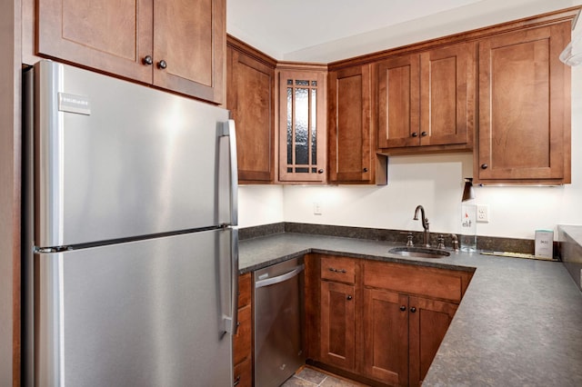 kitchen with glass insert cabinets, a sink, brown cabinetry, and appliances with stainless steel finishes