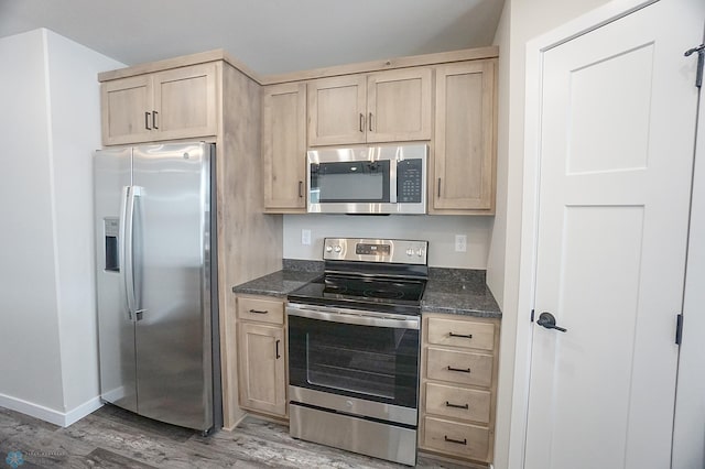 8072 Goldfinch Dr, Horace, ND 58047 - kitchen featuring stainless steel appliances, light brown cabinetry, light wood-type flooring, baseboards, and dark stone counters
