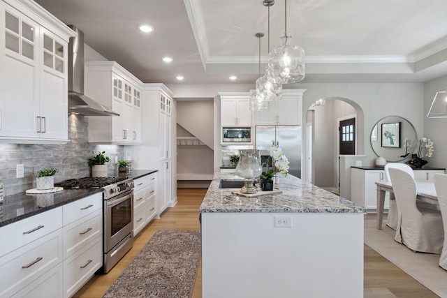 3725 Queensland Ln N, Plymouth, MN 55446 - kitchen featuring a raised ceiling, appliances with stainless steel finishes, a center island, wall chimney range hood, and arched walkways