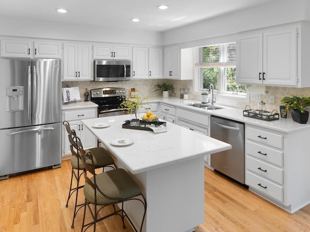 8118 Currant Pl, Eden Prairie, MN 55347 - kitchen featuring appliances with stainless steel finishes, tasteful backsplash, white cabinetry, a kitchen bar, and recessed lighting
