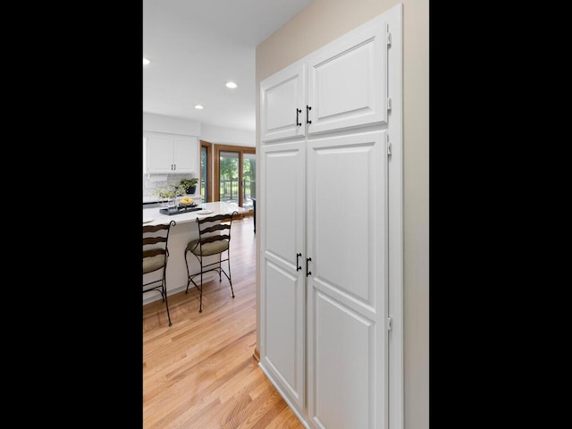 8118 Currant Pl, Eden Prairie, MN 55347 - kitchen with a kitchen breakfast bar, white cabinets, light wood-style floors, recessed lighting, and tasteful backsplash