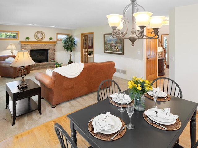 8118 Currant Pl, Eden Prairie, MN 55347 - dining room with a chandelier, a wainscoted wall, light wood-type flooring, and a fireplace