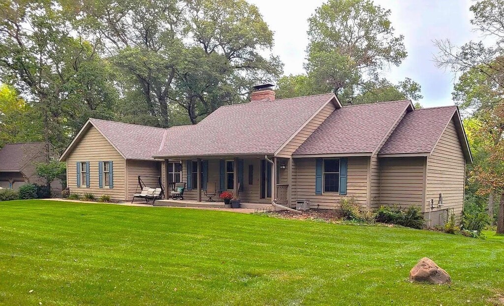 rear view of property featuring a yard, a chimney, and a shingled roof