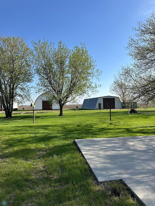 view of grassy yard featuring an outbuilding, a garage, and an outdoor structure