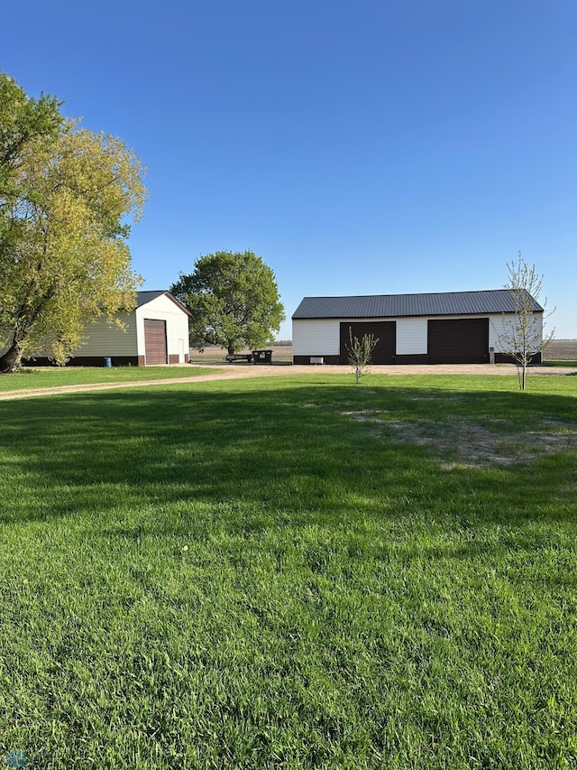 view of grassy yard with an outbuilding, an outdoor structure, and a detached garage
