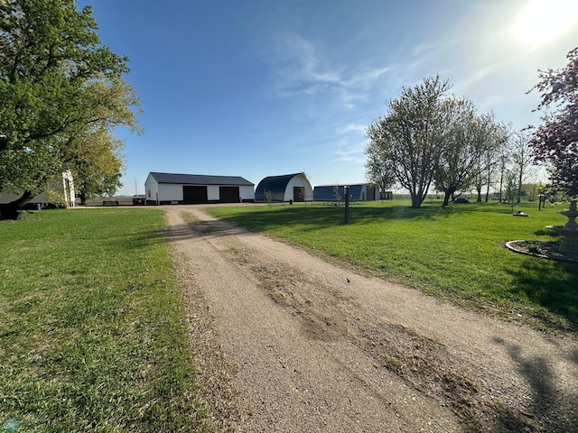 view of front of house with dirt driveway, an outdoor structure, a front lawn, and a garage