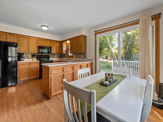 15029 Tyacke Dr, Burnsville, MN 55306 - kitchen with decorative backsplash, light countertops, light wood finished floors, a sink, and black appliances