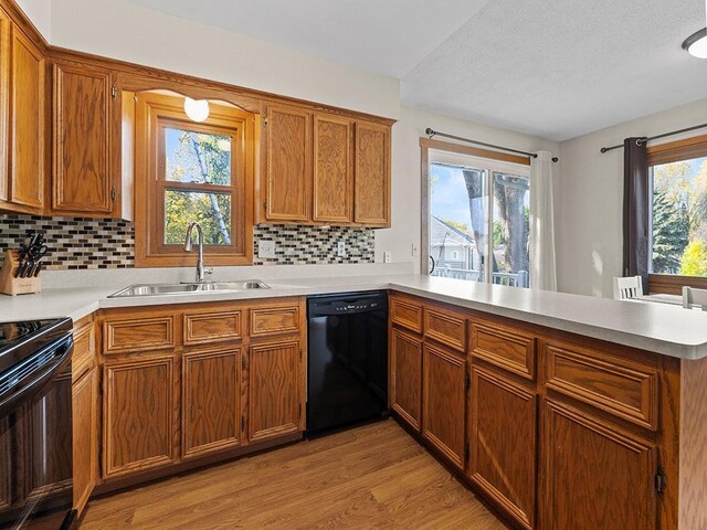 15029 Tyacke Dr, Burnsville, MN 55306 - kitchen with a healthy amount of sunlight, a sink, light wood-style flooring, a peninsula, and black appliances