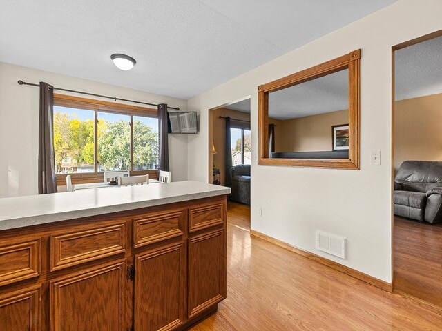 15029 Tyacke Dr, Burnsville, MN 55306 - kitchen with light countertops, visible vents, light wood finished floors, baseboards, and brown cabinets