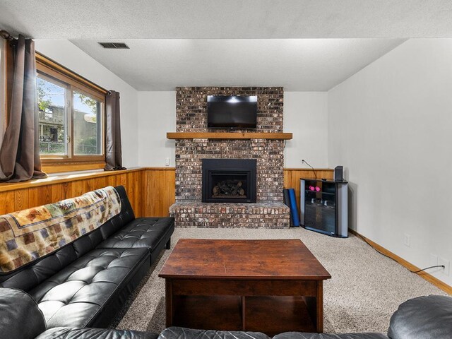 15029 Tyacke Dr, Burnsville, MN 55306 - carpeted living area featuring a textured ceiling, visible vents, wooden walls, a fireplace, and wainscoting