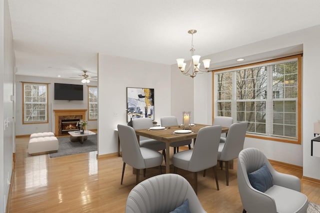 15767 Porchlight Ln, Eden Prairie, MN 55347 - dining area with light wood finished floors, baseboards, a fireplace, and ceiling fan with notable chandelier