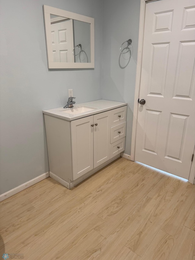 bathroom with baseboards, vanity, and wood finished floors