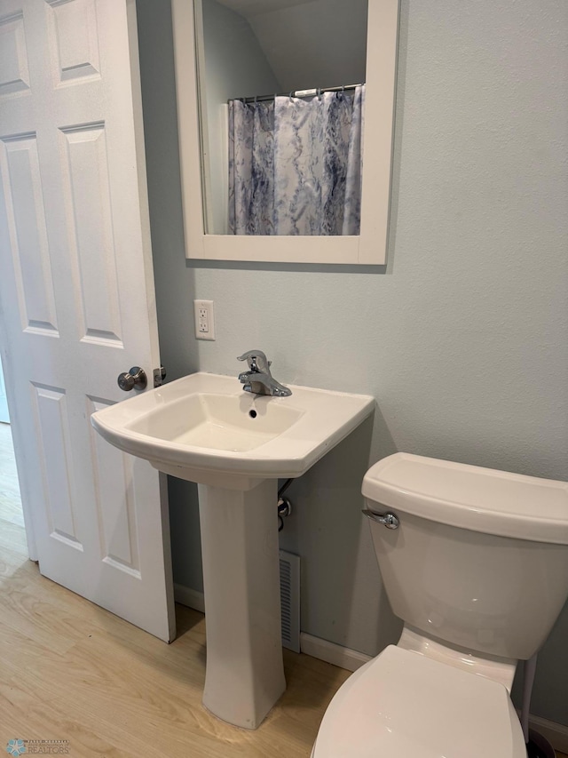 full bath with wood finished floors, a shower with shower curtain, and toilet