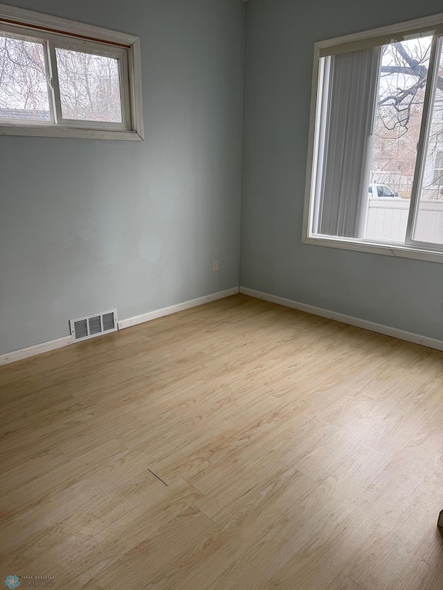spare room featuring visible vents, baseboards, and wood finished floors