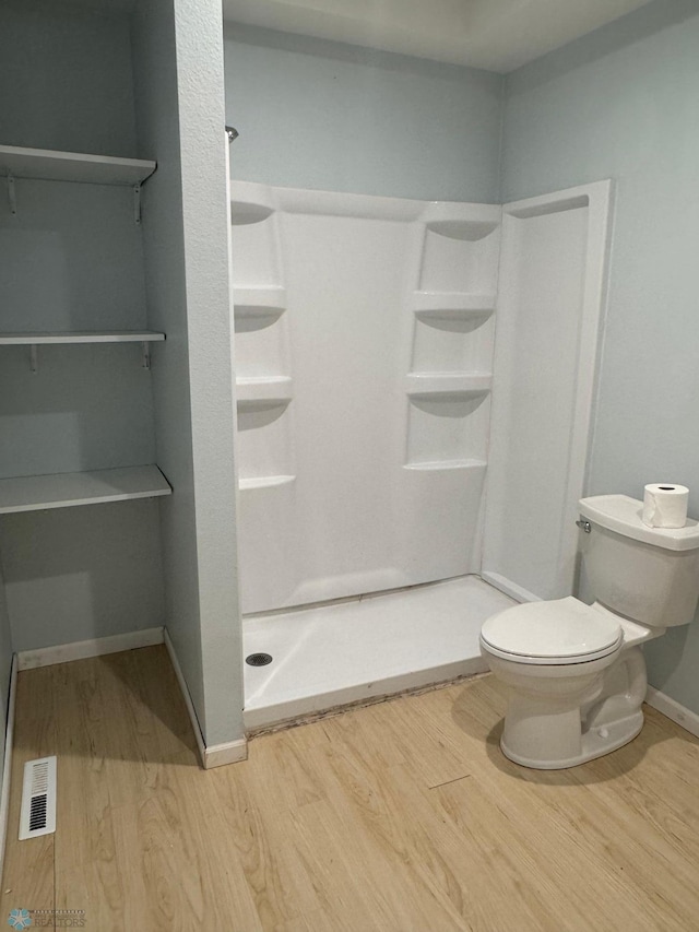 full bathroom with toilet, wood finished floors, a stall shower, baseboards, and visible vents