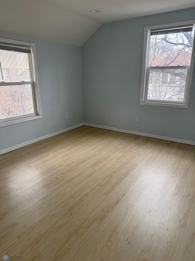 additional living space featuring baseboards, vaulted ceiling, wood finished floors, and a wealth of natural light