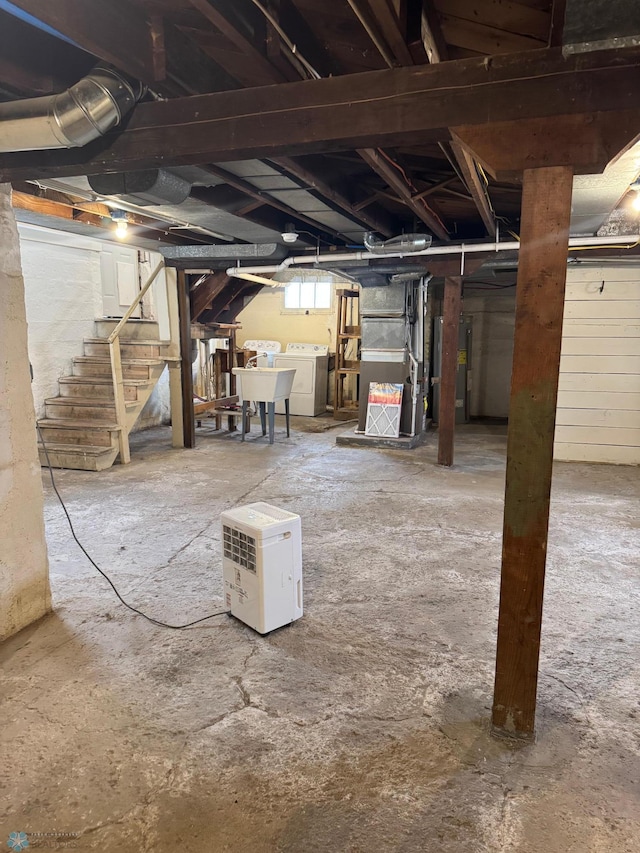 below grade area featuring independent washer and dryer, stairs, heating unit, and a sink