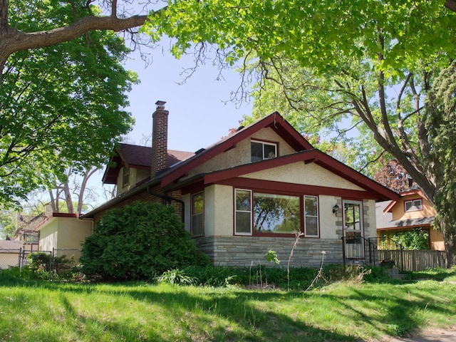 view of property exterior featuring stone siding, stucco siding, and a chimney
