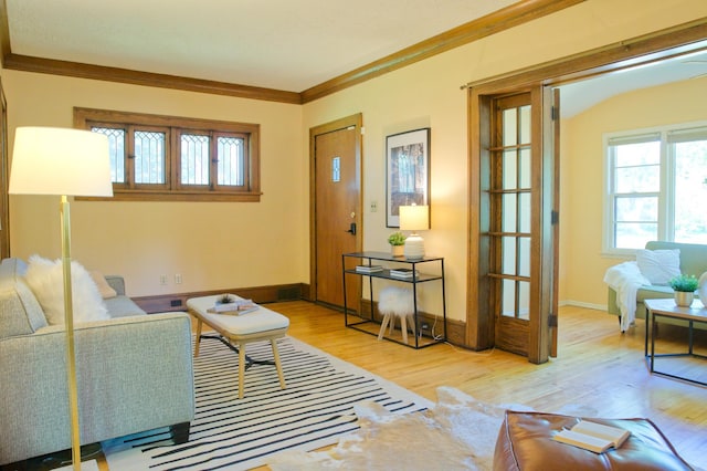living area with wood finished floors, ornamental molding, and baseboards