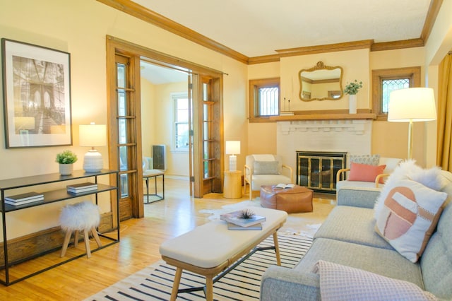 living area featuring crown molding, wood finished floors, a brick fireplace, and baseboards