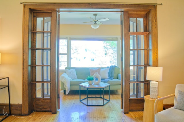 living area with a ceiling fan and wood-type flooring