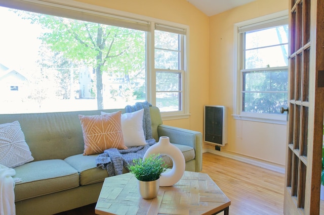 sitting room with plenty of natural light, wood finished floors, heating unit, baseboards, and vaulted ceiling