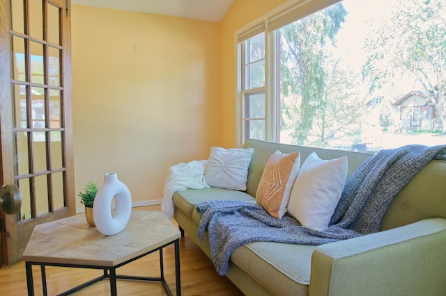 living area with wood finished floors, baseboards, and lofted ceiling