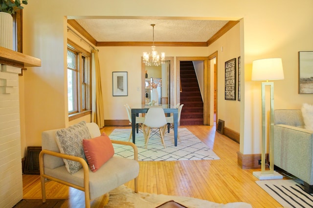 dining room with stairway, ornamental molding, light wood finished floors, a chandelier, and baseboards