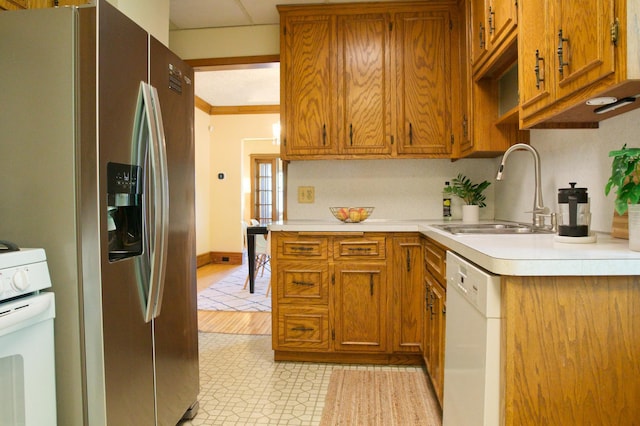 kitchen with white appliances, a sink, light countertops, brown cabinets, and ornamental molding