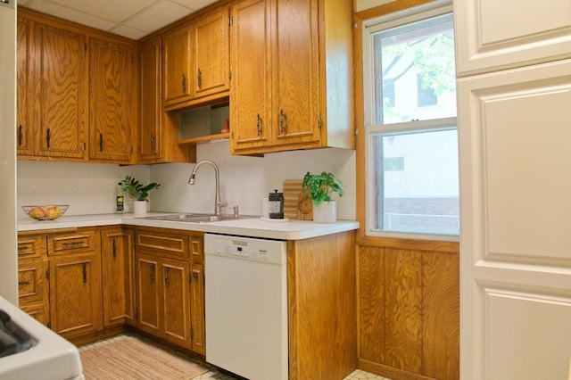 kitchen with white dishwasher, a sink, brown cabinets, and light countertops
