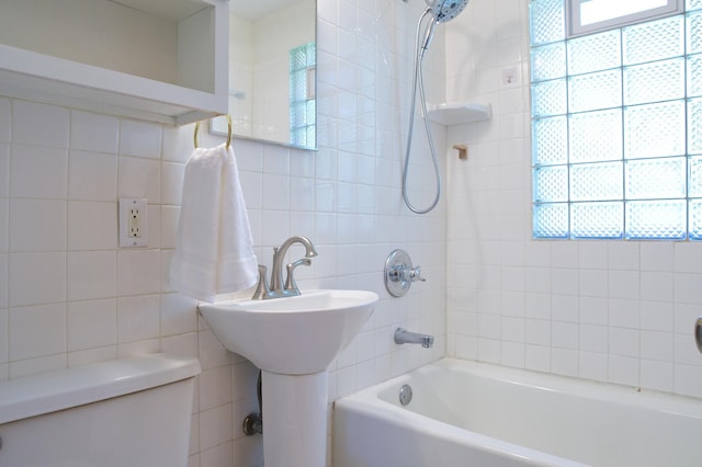 bathroom featuring tile walls, toilet, and washtub / shower combination