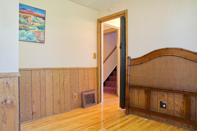 hall featuring wainscoting, wood finished floors, wood walls, and stairway