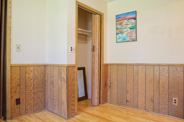 hall featuring wainscoting, wooden walls, and wood finished floors