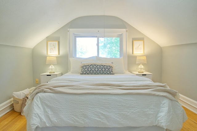 bedroom featuring vaulted ceiling, light wood-style floors, and baseboards