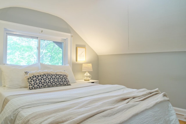 bedroom with lofted ceiling and baseboards
