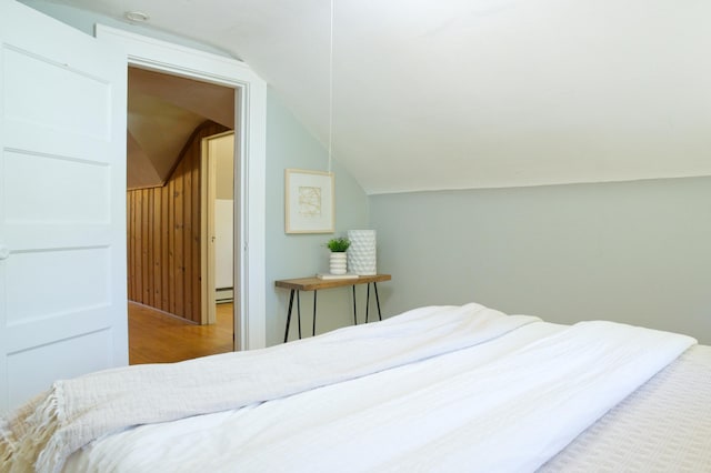 bedroom featuring vaulted ceiling, wood finished floors, and a baseboard heating unit