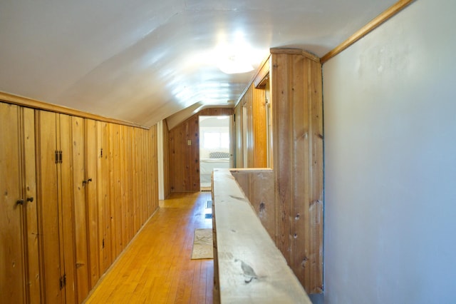 bonus room featuring vaulted ceiling, light wood finished floors, and wood walls