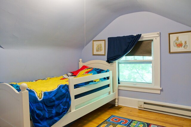 bedroom with a baseboard heating unit, vaulted ceiling, and wood finished floors