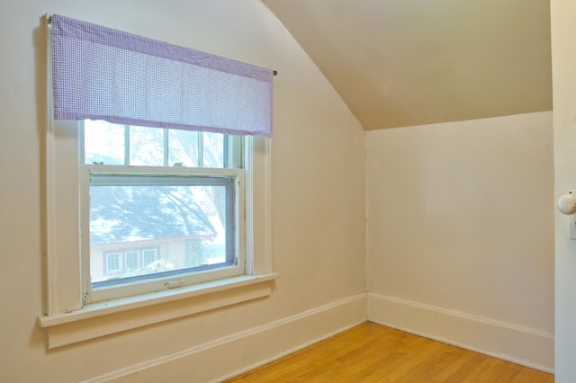 additional living space with vaulted ceiling, plenty of natural light, wood finished floors, and baseboards