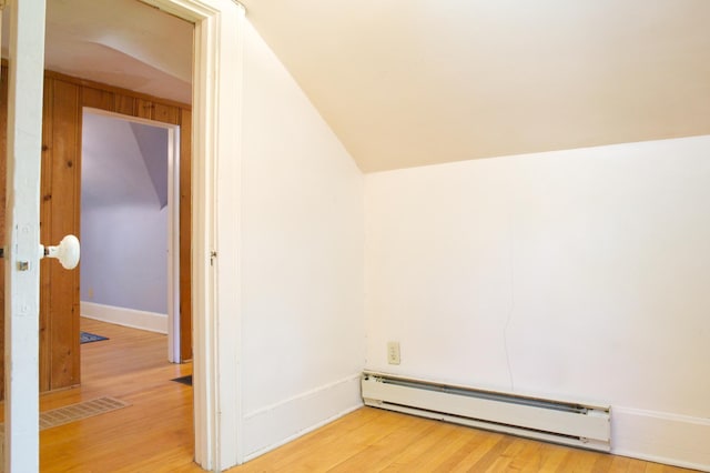 empty room featuring a baseboard radiator, light wood finished floors, lofted ceiling, and baseboards