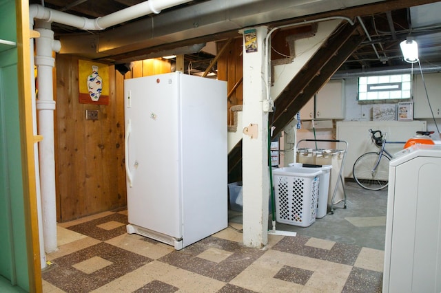 below grade area featuring freestanding refrigerator, washer / dryer, and tile patterned floors