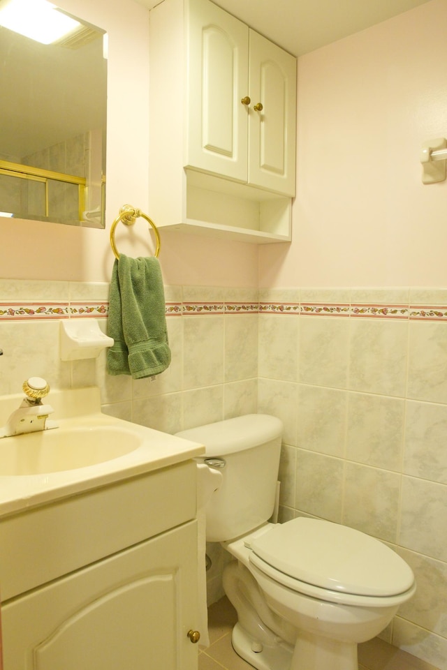 full bathroom featuring tile walls, vanity, a shower, toilet, and a wainscoted wall