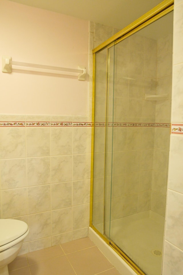 full bath with a stall shower, tile patterned floors, tile walls, and toilet