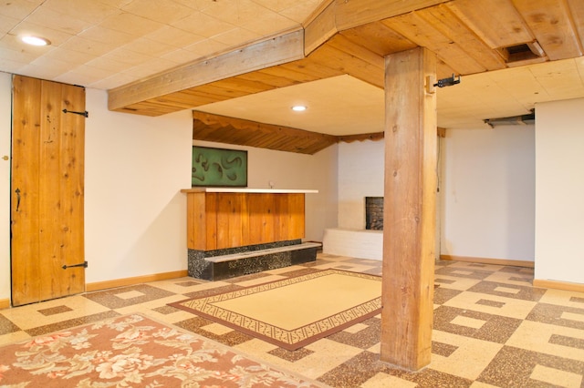 finished basement with baseboards, tile patterned floors, recessed lighting, and bar