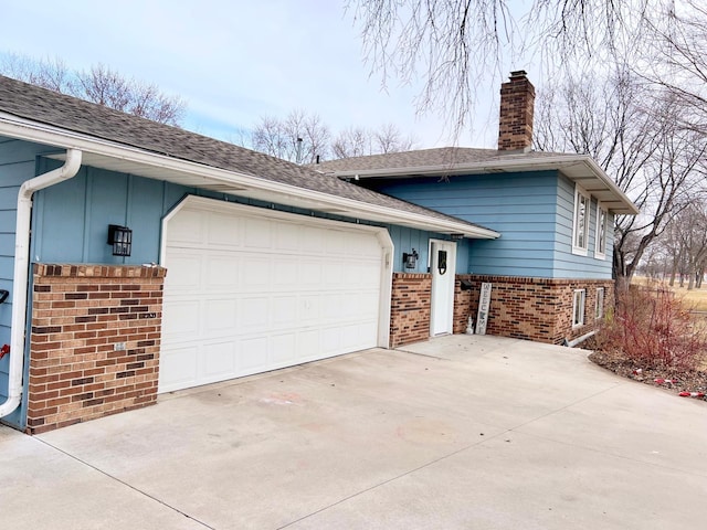 view of home's exterior featuring a chimney, a garage, brick siding, roof with shingles, and driveway