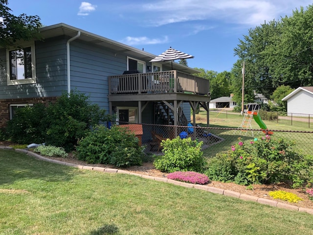 rear view of property with fence, a lawn, a deck, and stairway
