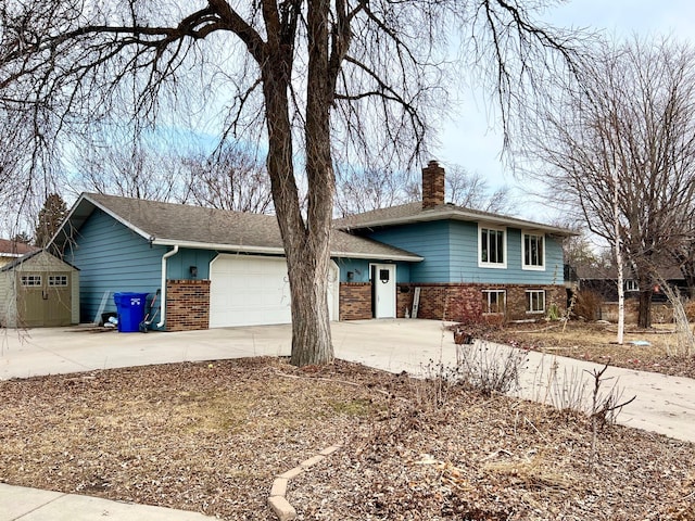 tri-level home featuring a chimney, brick siding, concrete driveway, and an attached garage